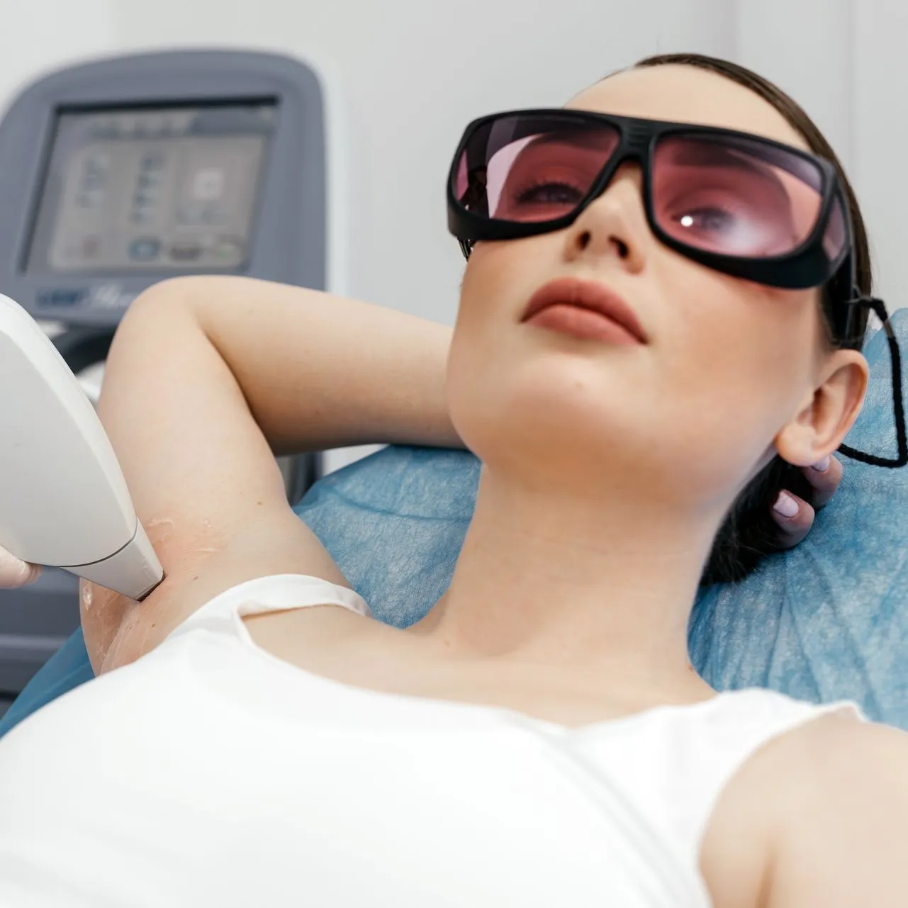 A woman is getting her armpit hair removed by a laser.